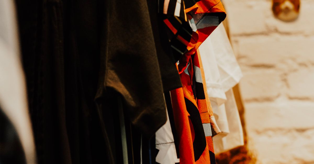 Colorful vintage clothing on rails set against a brick wall in a boutique setting.